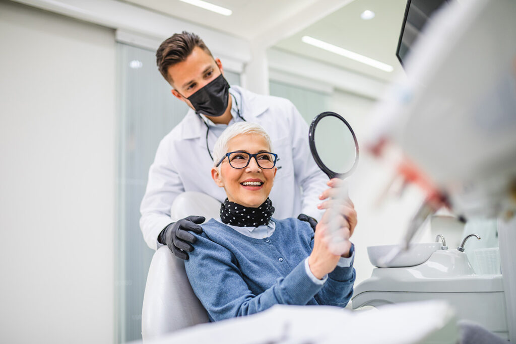 Older patient admiring her smile after dental treatment