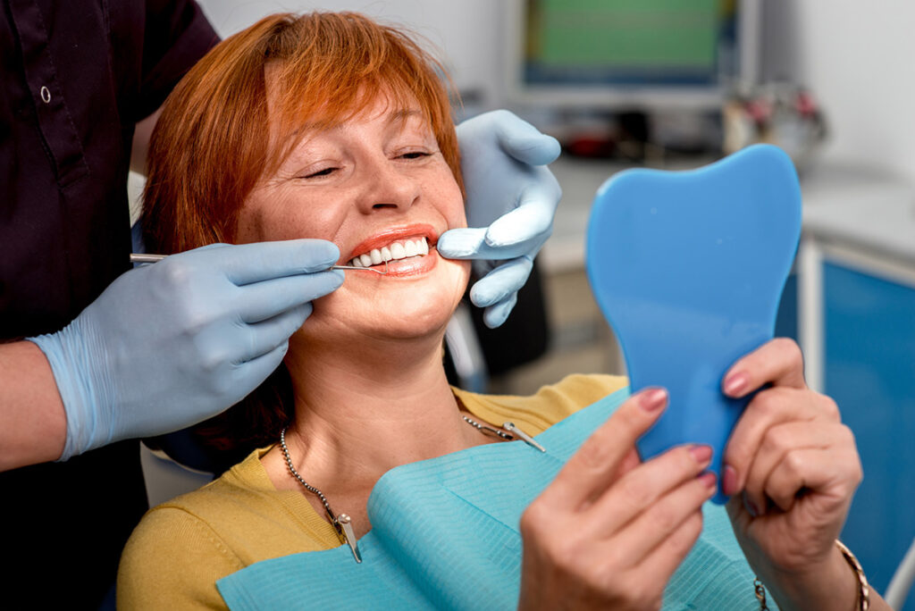Dentist examining a patient who is holding a mirror