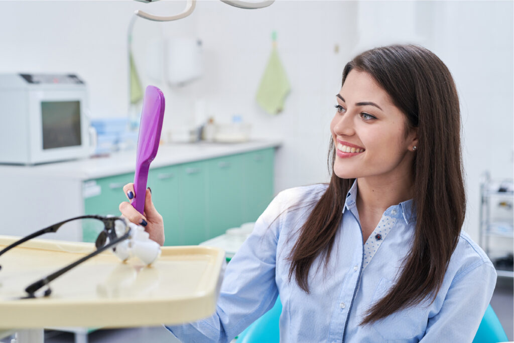 Dental patient admiring her smile in a handheld mirror